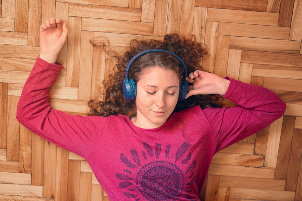 Young woman laying on the floor with headphones
