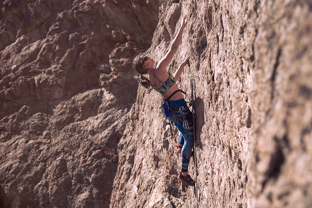 Young woman with climbing equipment on a rock wall