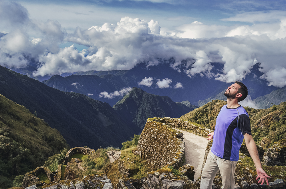 A man enjoying the valley landscape on inca trail ruins